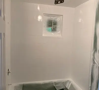 Refinished white bathtub and shower surround with glossy wall panels