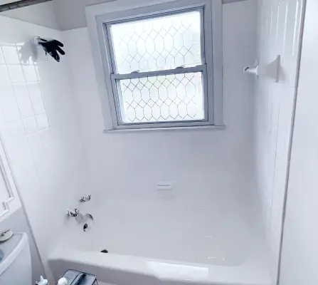Refinished white bathtub and shower surround with frosted window