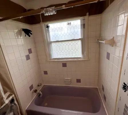 Purple bathtub before refinishing with tiled shower surround
