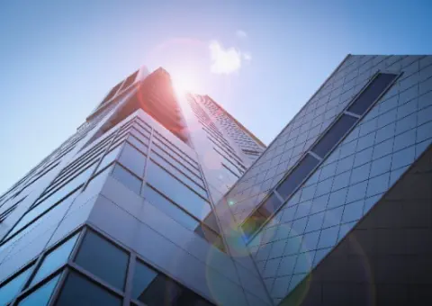 Modern glass office building with reflective windows and blue sky