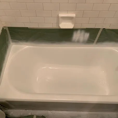 Refinished white bathtub with subway tile surround and soap dish