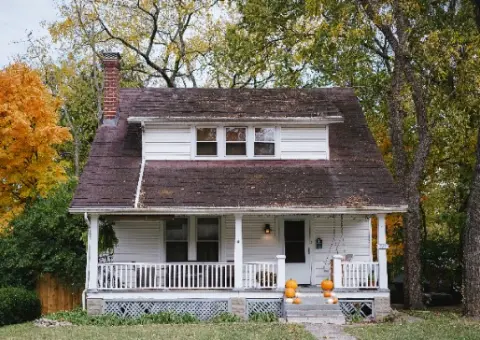 White single-family house with a covered front porch and mature trees