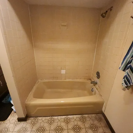 Beige bathtub and tiled shower surround before refinishing
