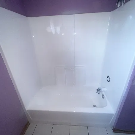 Refinished white bathtub and shower surround with glossy wall panels