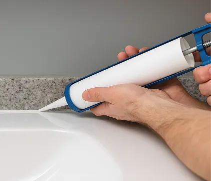 Applying caulk around a bathtub with a caulking gun