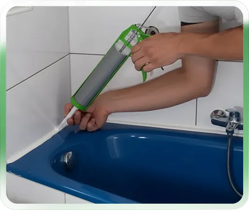 Applying caulk around a blue bathtub with a caulking gun