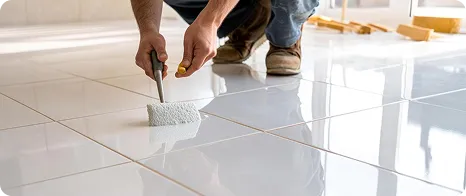 Technician applying grout to white floor tiles