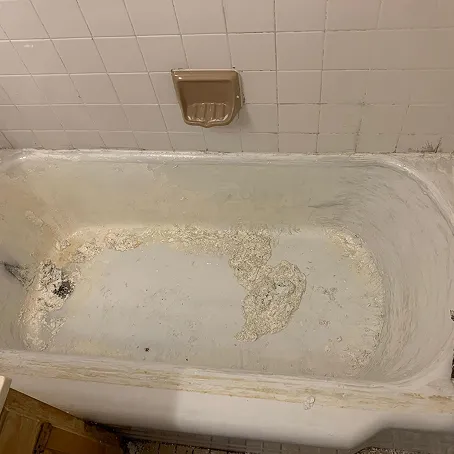Damaged bathtub with peeling surface before refinishing
