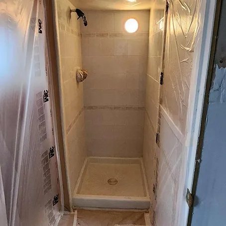 Refinished walk-in shower with glossy white tiled walls