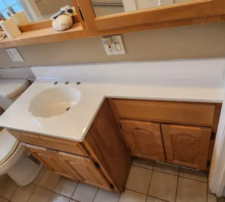 Refinished white bathroom vanity with integrated sink and wood cabinets