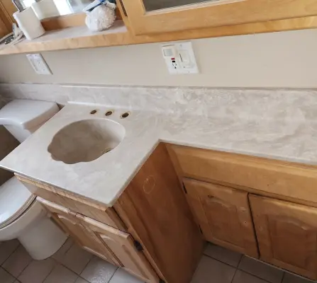 Refinished marble-look bathroom vanity with integrated sink and wood cabinets