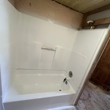 Refinished white bathtub and shower surround with glossy wall panels
