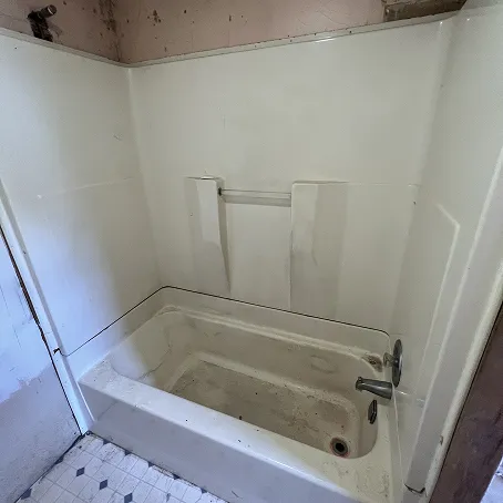 Worn white bathtub and shower surround before refinishing